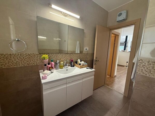 Un baño con un espejo grande, dos lavamanos y un perchero para toallas.