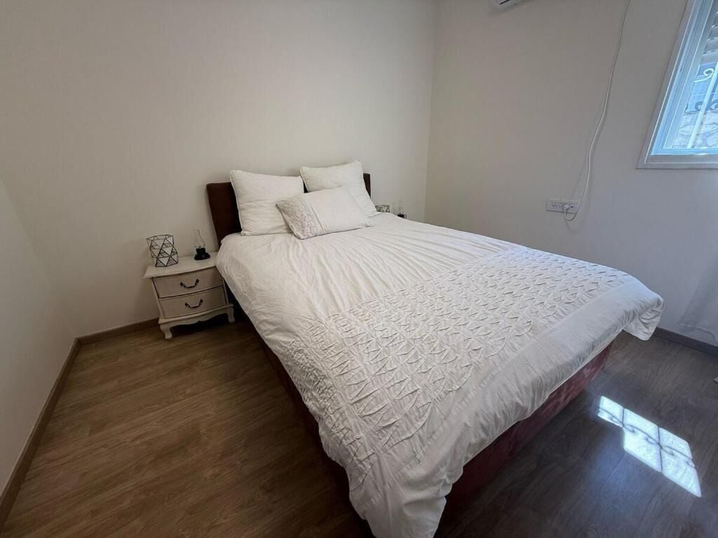 Ein Schlafzimmer mit einem großen Bett, einem Nachttisch und einem Fenster.