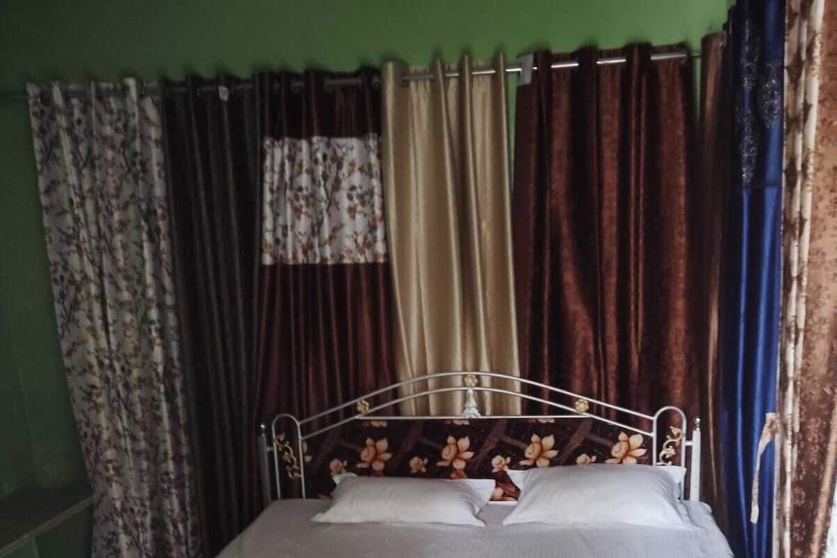 A single bed with a metal frame, white bedding, and a floral-patterned blanket.