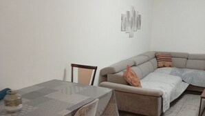 A dining area with a table and chairs, a grey sofa with cushions, and a patterned rug. - Quiet, spacious apartment in an ideal location (Avignon)
