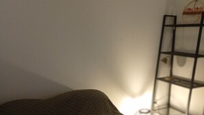 A room with a bed, a small shelf unit, and a wall-mounted light fixture. - Quiet, spacious apartment in an ideal location (Avignon)