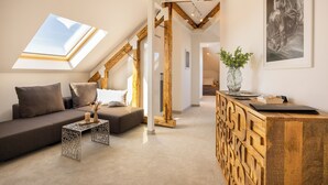 Un moderno loft con soffitto spiovente, una scrivania in legno integrata, un divano e un lucernario.