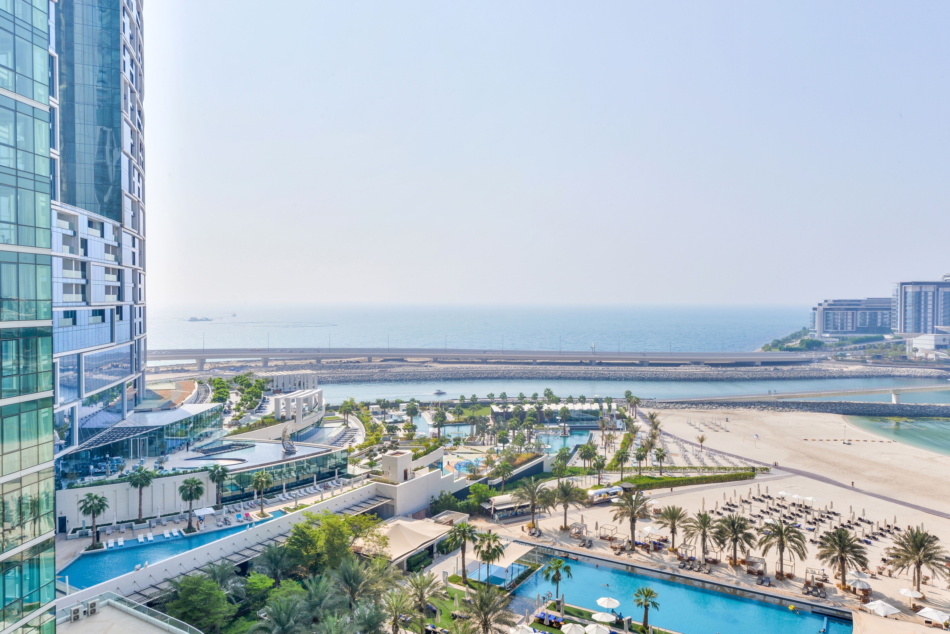 Ein Hochhaus-Hotel mit Poolbereich, Zugang zum Strand und Meerblick.