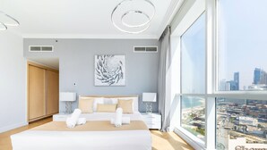 A modern hotel room with a large bed, two bedside tables with lamps, a city view, and a large window. - Al Bateen Ultra Luxe 5BR I Private Beach (Dubai)