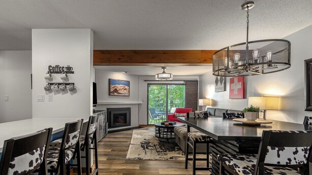 A modern kitchen with a central island, a dining area with a chandelier, and a cozy seating area with a fireplace. - Timber Run — Your Perfect Steamboat Getaway, private shuttle to resort (Steamboat Springs)