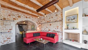 Ein gemütliches Wohnzimmer mit einem roten Sofa, Steinwänden, einem Kamin und einer Treppe, die in einen anderen Bereich führt.