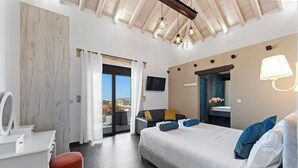 Ein modernes Hotelzimmer mit Bett, Schreibtisch, Sessel, Fernseher und einem Balkon mit Blick.