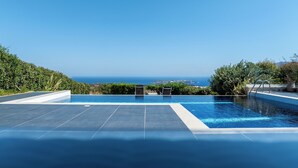 Ein Pool mit freiem Blick auf den Ozean und einer gefliesten Liegefläche.