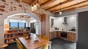 Eine moderne Küche mit Holzschränken, ein Essbereich mit Holztisch und gelben Stühlen sowie eine Steinwand.