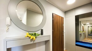 Un couloir avec une porte en bois, un miroir et un téléphone fixé au mur.