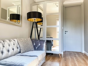 A modern living room with a sofa, a floor lamp, and a large mirror. - BP Gray Premium (Toruń)
