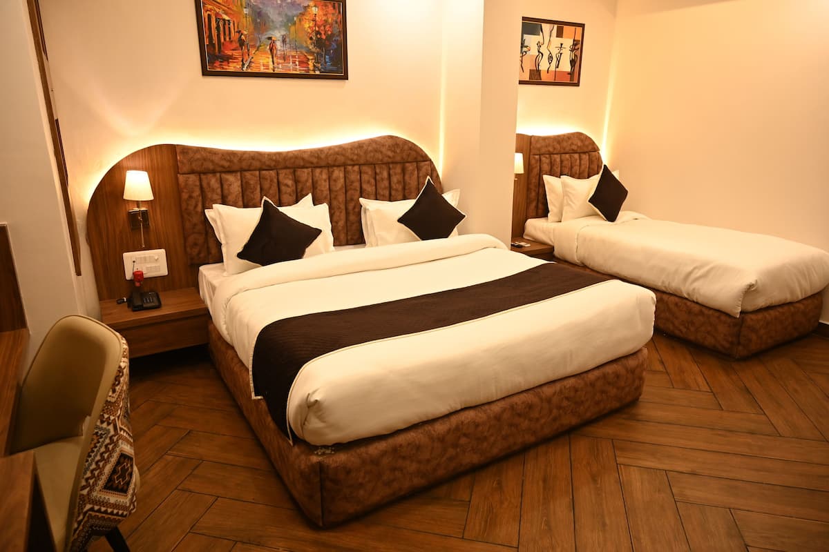Habitación de hotel con dos camas, suelo de madera, un escritorio con silla y obras de arte en las paredes.