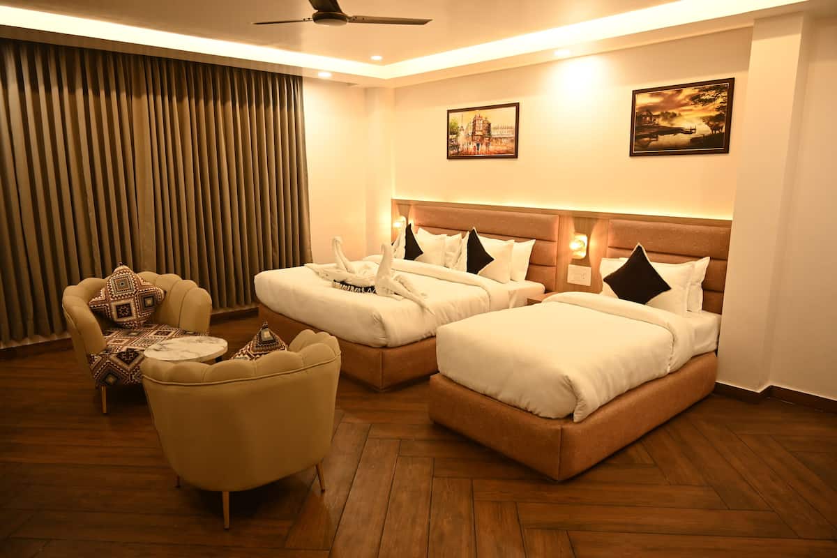 Habitación de hotel con dos camas, un sofá y un ventilador de techo.