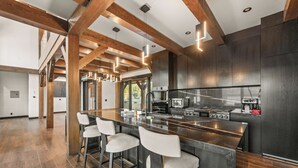 A modern kitchen with a central island, bar stools, and a large window. - LAKEFRONT - 5 STAR 4,500 sqft! Hot Tub, Fire Pit, Dock, Fireworks & Fireworks (Big Bear Lake)