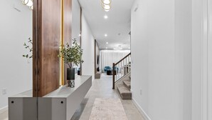 Ein moderner Flur mit einer Wand als Holzdekor, einer eingebauten Sitzbank und einer Treppe, die eine weitere Ebene hinaufführt.
