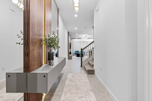 A modern hallway with a wooden accent wall, a built-in bench, and a staircase leading to another level. - 5BR house sleeps 14 with private pool in kissimmee (Kissimmee)