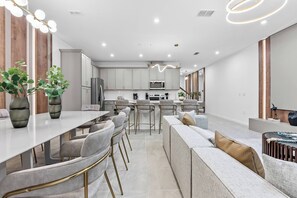 A modern kitchen with white cabinets, a central island, and bar stools. - 5BR house sleeps 14 with private pool in kissimmee (Kissimmee)