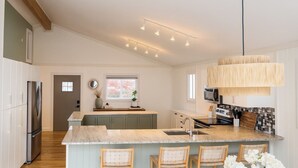 Een moderne keuken met een centraal eiland, inbouwapparatuur en een hangende lamp.