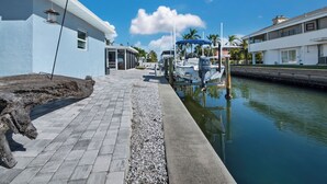 A marina with a docked boat, a paved walkway, and a building with a blue exterior. - Longboat Key - Choose Joy - Relax on the Beach (Longboat Key)