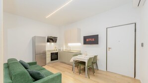 A compact living space with a kitchenette, a dining area, and a green sofa. - Torino | San Domenico Home (Torino)