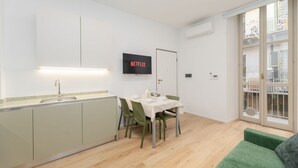 A compact living space with a kitchenette, dining area, and a green sofa. - Torino | San Domenico Home (Torino)