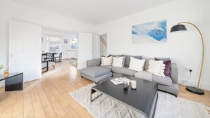 A modern living room with a grey sectional sofa, a black coffee table, and a floor lamp. - Hyde Park 3BR Retreat by Marble Arch (London)