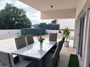 An outdoor patio with a glass-top table, wicker chairs, and a potted plant. - 3-bedroom villa in Raslina with 3 air condition.
Near beach,Šibenik, Vodice... (Raslina)