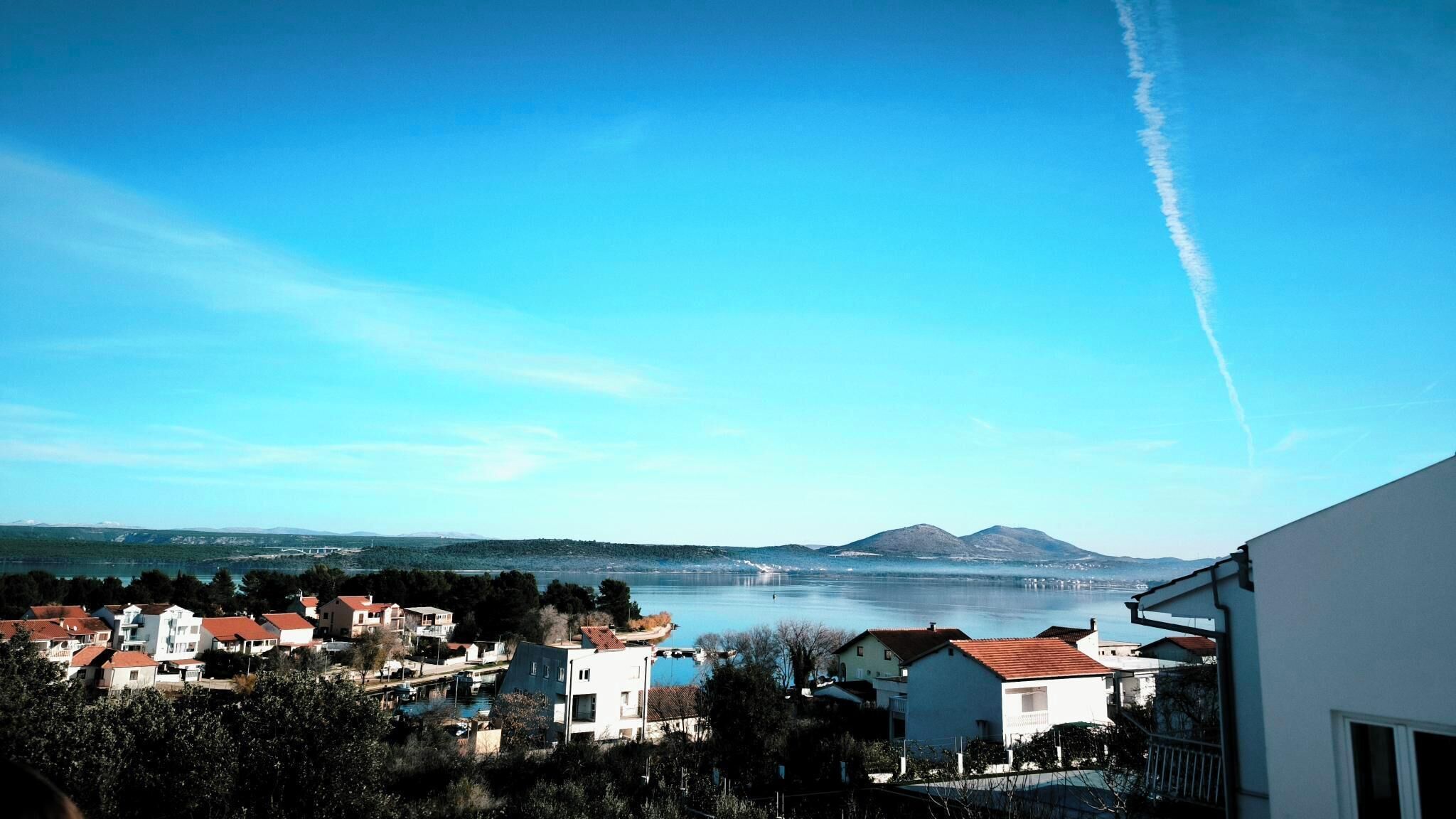 Un pueblo costero con casas, un puente y una montaña al fondo.