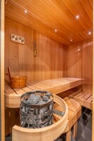 Uma sauna de madeira com bancos, um balde e um recipiente metálico para pedras.
