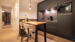 Une cuisine moderne avec des meubles de couleur sombre, une table en bois et un four encastré.