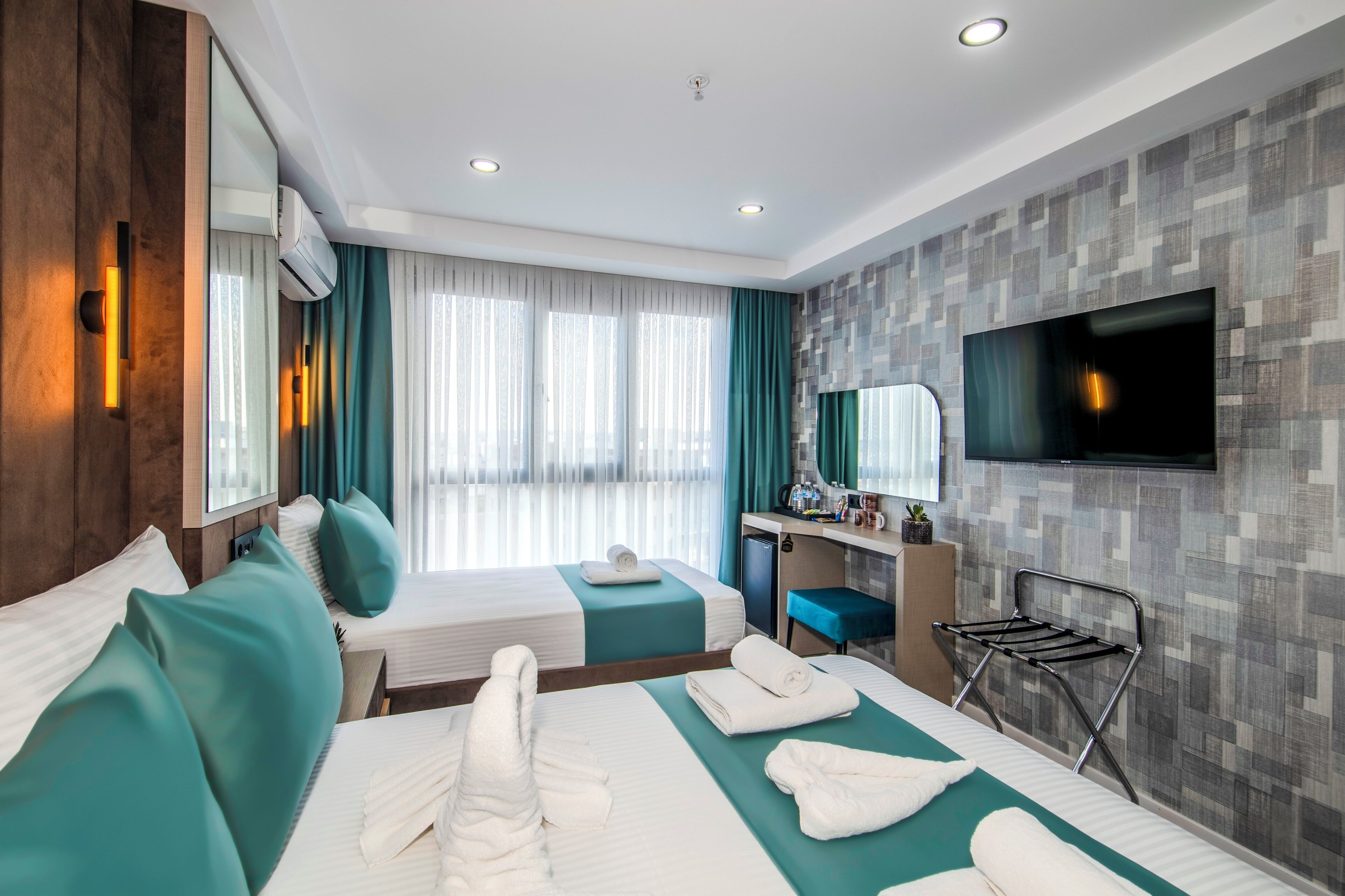 A hotel room with two beds, a desk, a TV, and a bathroom.