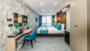 A modern hotel room with a large bed, a desk with a chair, a small kitchenette, and a bathroom with a shower and toilet. - Cosinüs Airport Hotel (Arnavutköy)