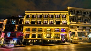 A hotel with a classic facade, multiple windows, and a well-lit entrance. - Cosinüs Airport Hotel (Arnavutköy)