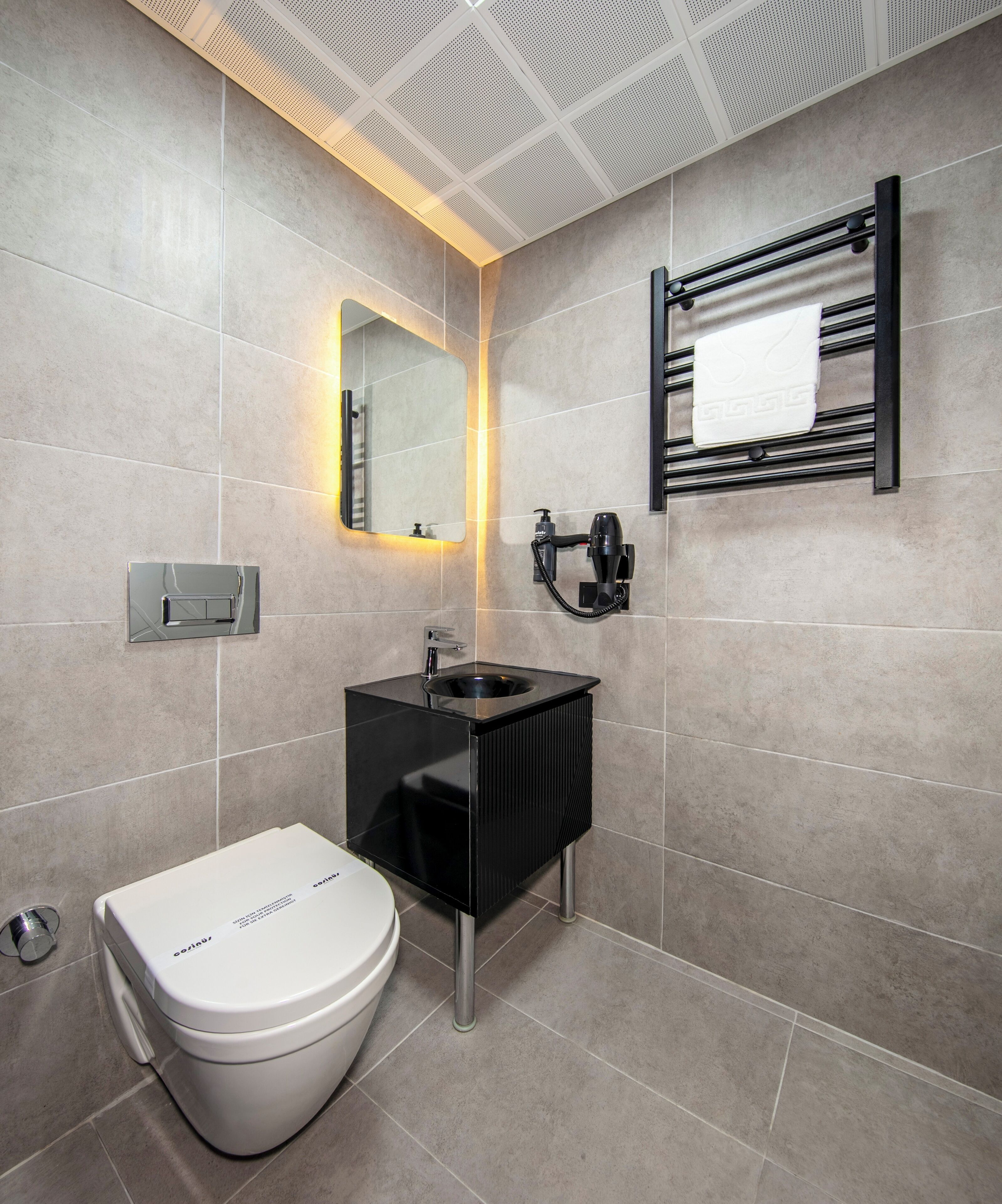 A modern bathroom with a toilet, sink, and mirrors.
