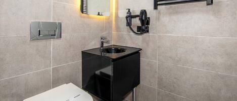 A modern bathroom with a toilet, sink, and mirrors.