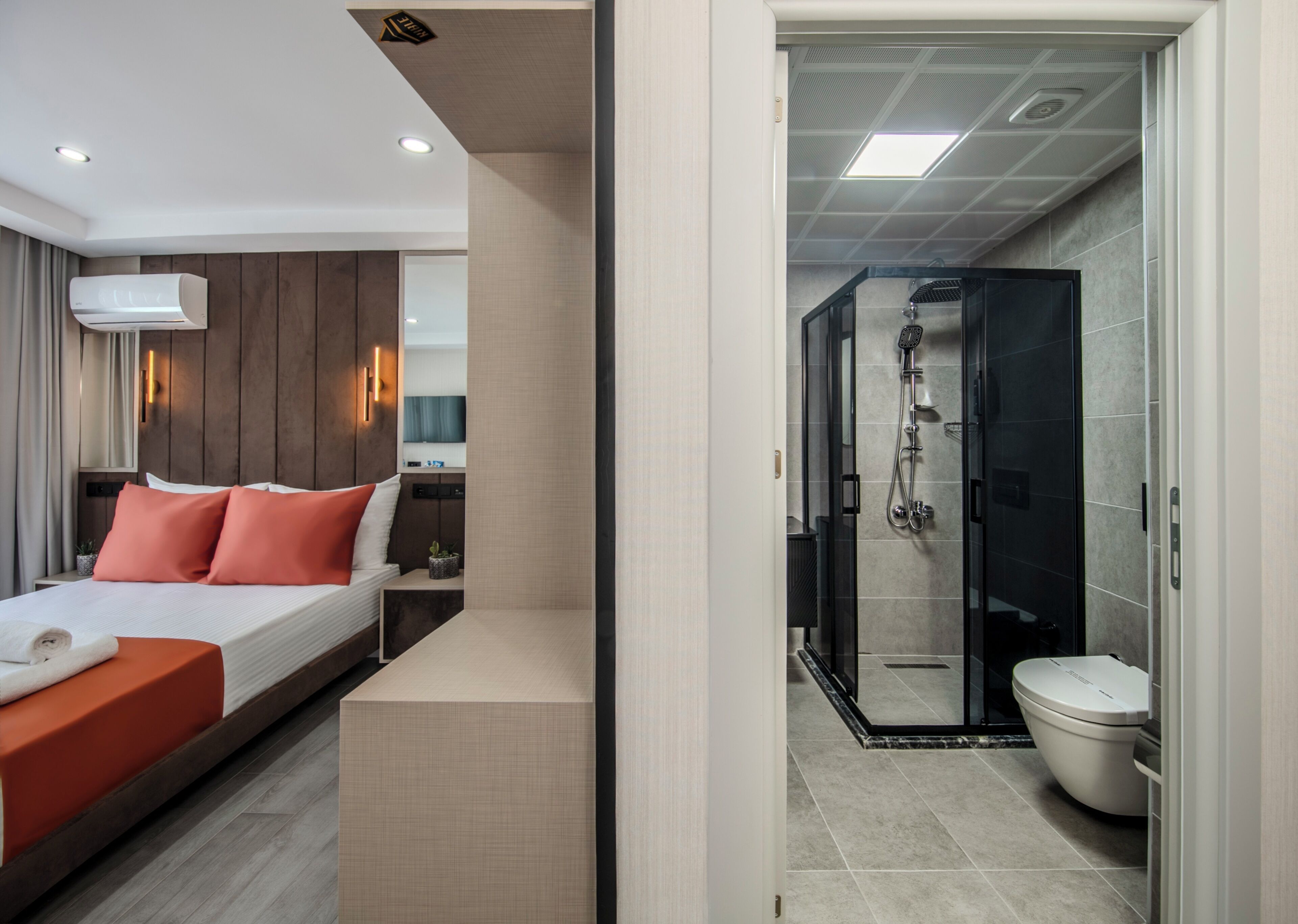 Ein modernes Hotelzimmer mit einem Bett, einem Nachttisch und einem Duschbereich mit Glastür.