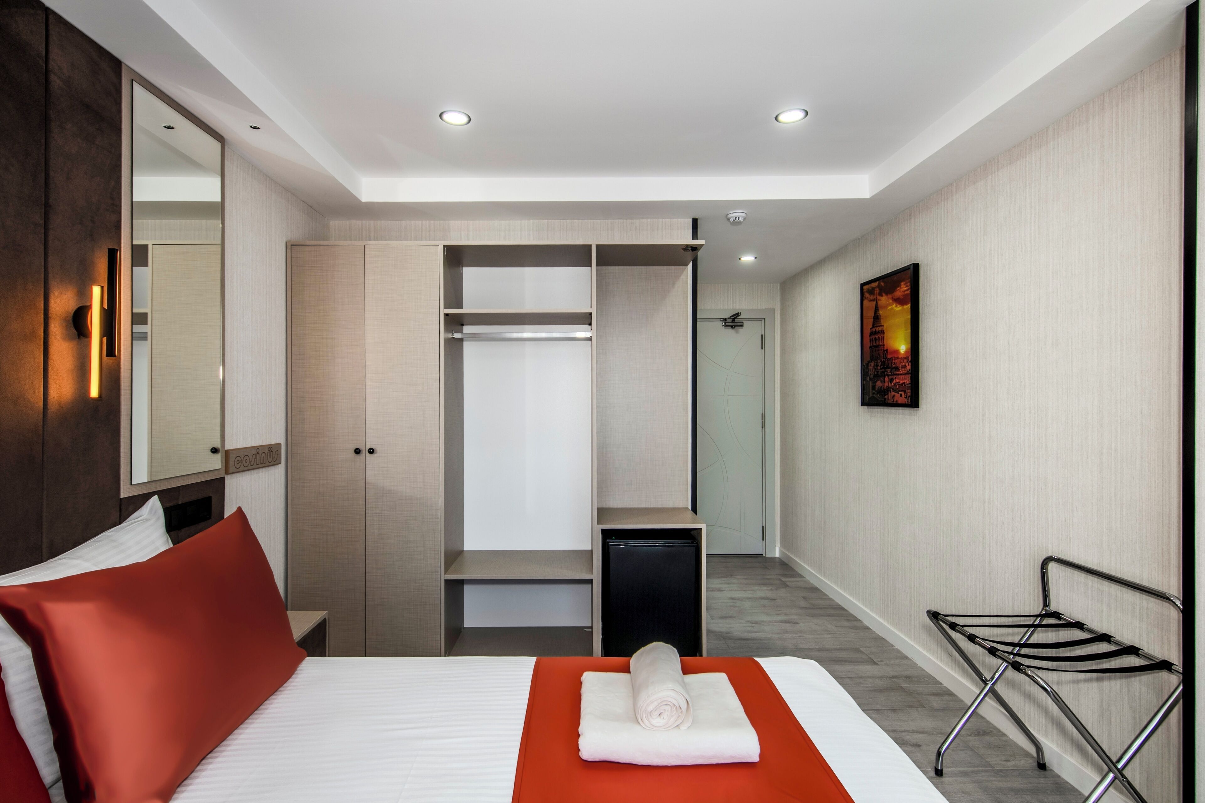 A hotel room with a bed, a wardrobe, a desk, and a shower area.