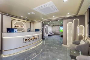 Ein Hotel-Empfangsbereich mit modernem Design, inklusive einer Rezeption, einer Sitzecke und Blick ins Hotel-Foyer.