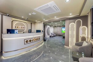 Zona de recepción de un hotel con diseño moderno, que incluye mostrador de recepción, área de estar y vistas al vestíbulo.