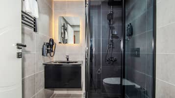 A modern bathroom with a glass-enclosed shower, a black vanity, and a towel rack.