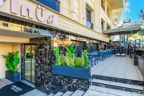 A hotel entrance with a modern design, featuring a reception desk, a seating area with tables and chairs, and a large planter with plants. - Cosinüs Airport Hotel (Arnavutköy)