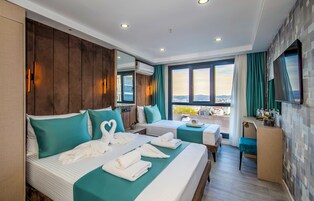 Habitación de hotel con dos camas, televisión, escritorio y vista a la ciudad.