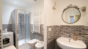 Une salle de bain équipée d’une douche, de toilettes et d’un lavabo, ainsi que d’un lave-linge.