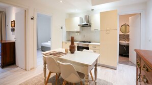 Une cuisine moderne avec des meubles blancs, un îlot central et un coin repas avec des chaises.
