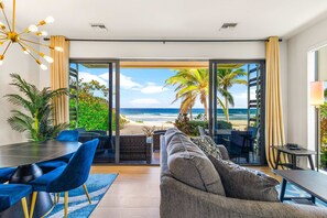 Un salon moderne doté d’une grande porte vitrée donnant sur un balcon avec vue sur la plage.