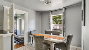Un comedor con una mesa, cuatro sillas y una ventana con cortinas.