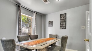 Un comedor con una mesa de mármol, seis sillas tapizadas y dos adornos en la pared.