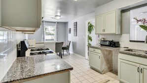 Una cocina moderna con armarios blancos, encimera de granito y microondas integrado.