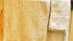 A towel rack with two towels against a yellow wall. - Lights of Kazinga Homestay (Kichwamba)