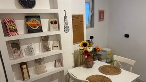 A dining area with a white table, two woven placemats, a vase with sunflowers, and a clock on the wall. - Comfort in the heart of Bari (Bari)